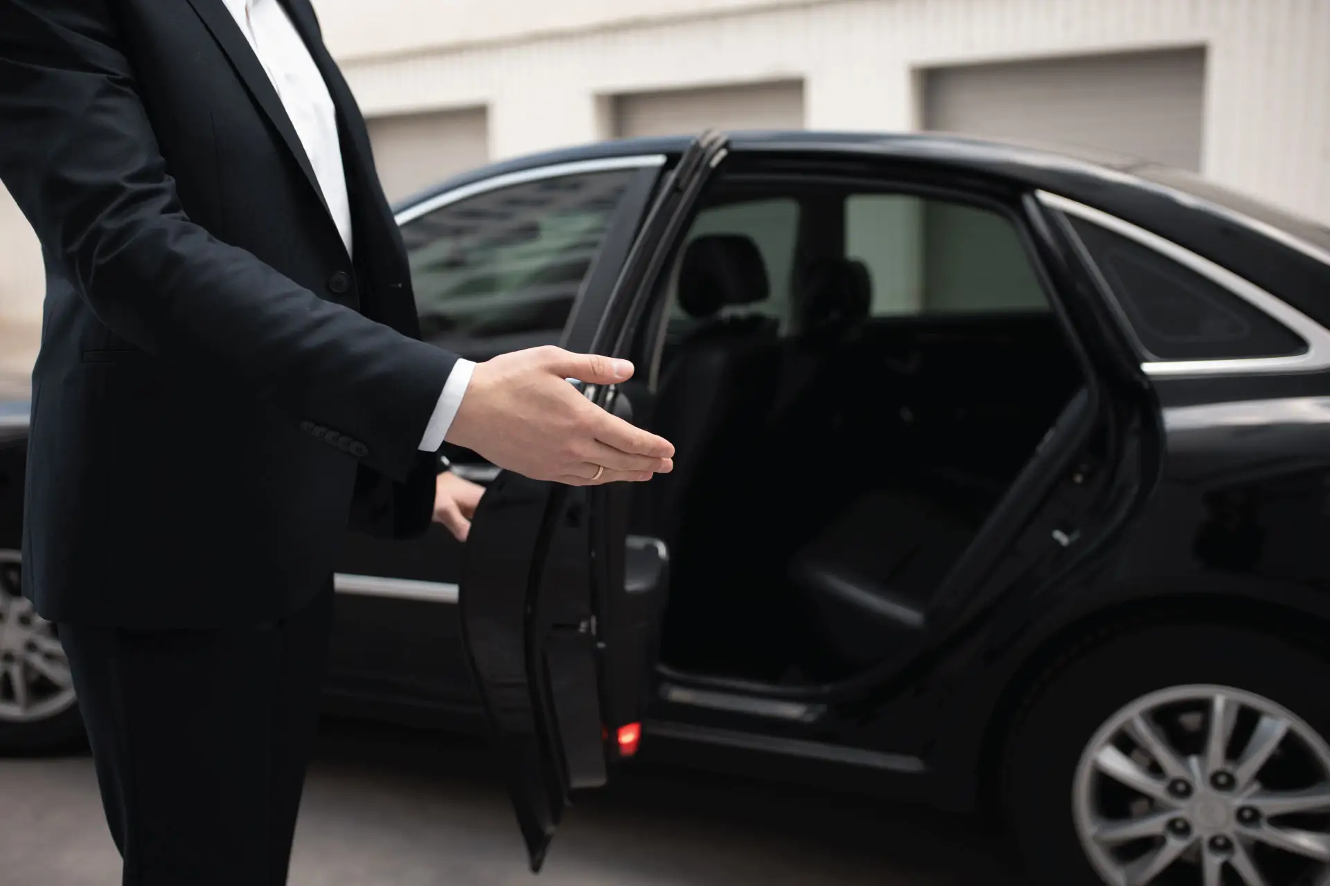 Professioneller Chauffeur neben einer Business-Limousine